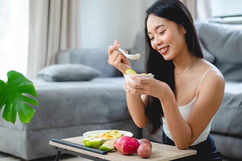 Mulher sorrindo enquanto saboreia sobremesa saudável