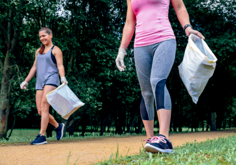 Duas mulheres praticando plogging em local arborizado