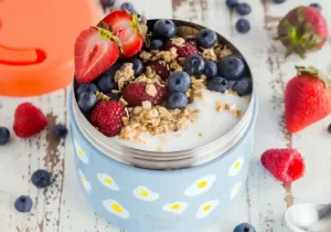 pote de metal com iogurte natural com granola, morango, amora e blueberry
