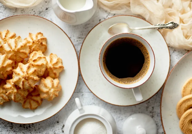 Biscoitos de coco proteico com café preto mesa com biscoitos de coco proteico com café preto e bolachas de coco no prato