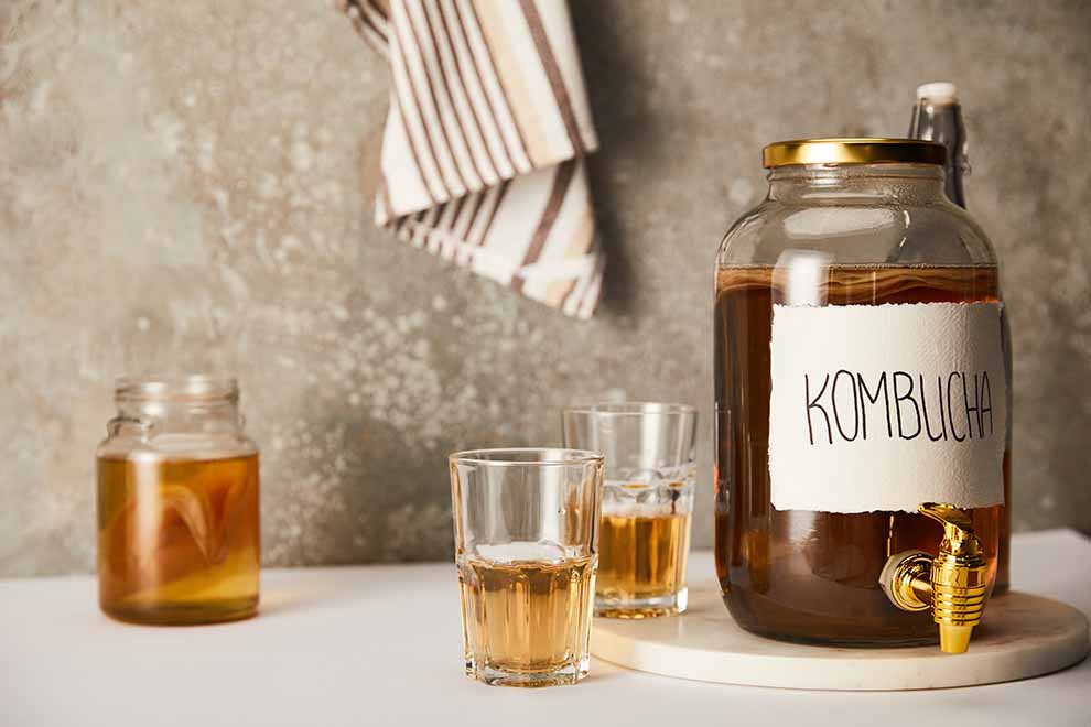 Jarros de kombucha e copos sobre mesa branca
