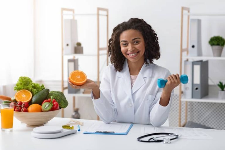 Nutricionista segurando uma fruta em uma mão e um peso de academia em outra