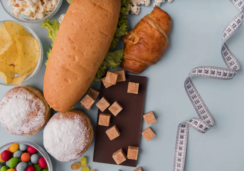 vista superior de alimentos não saudáveis com fita métrica do lado