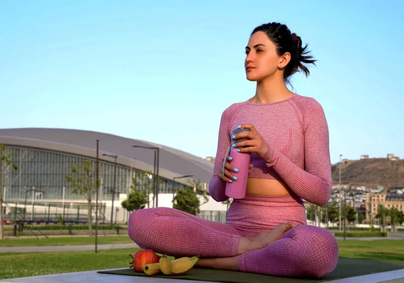 mulher sentada na grama tomando água de manhã