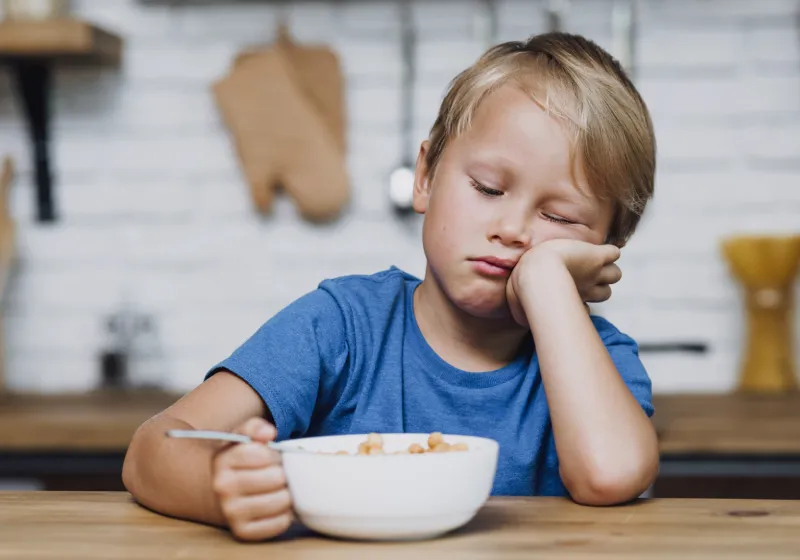seletividade alimentar infantil garoto desanimado não querendo comer seus cereais na mesa