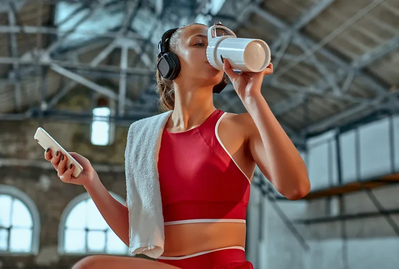 mulher sentada ouvindo música e tomando suplemento