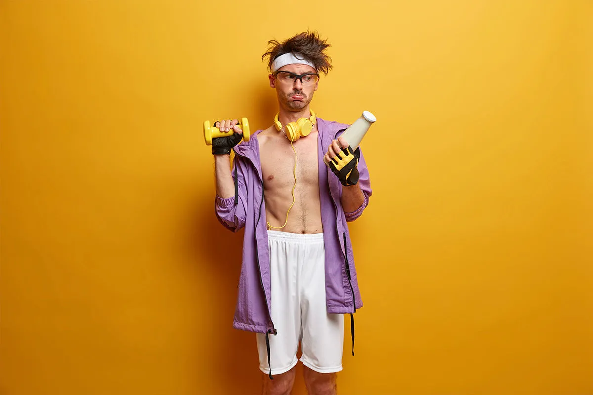 homem com a camisa aberta segurando um meso de academia e uma garrafa de leite 