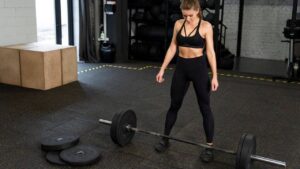 mulher na cademia se preparando para exercício com peso