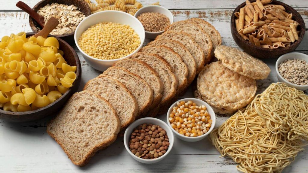 Em cima de uma mesa de madeira, alimentos ricos em carboidrato.