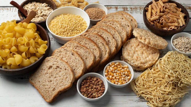 Em cima de uma mesa de madeira, alimentos ricos em carboidrato.