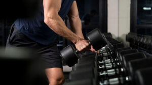 homem na academia pegando um halter de peso