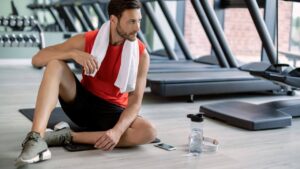 homem sentado no chão da academia