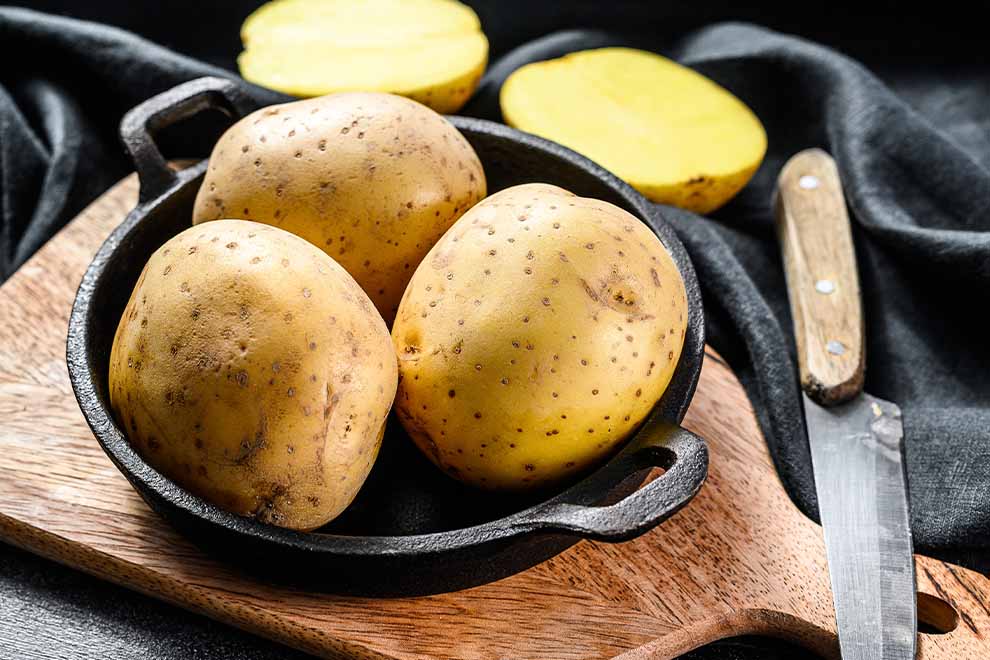 Batatas frescas em panela de ferro sobre tábua de madeira