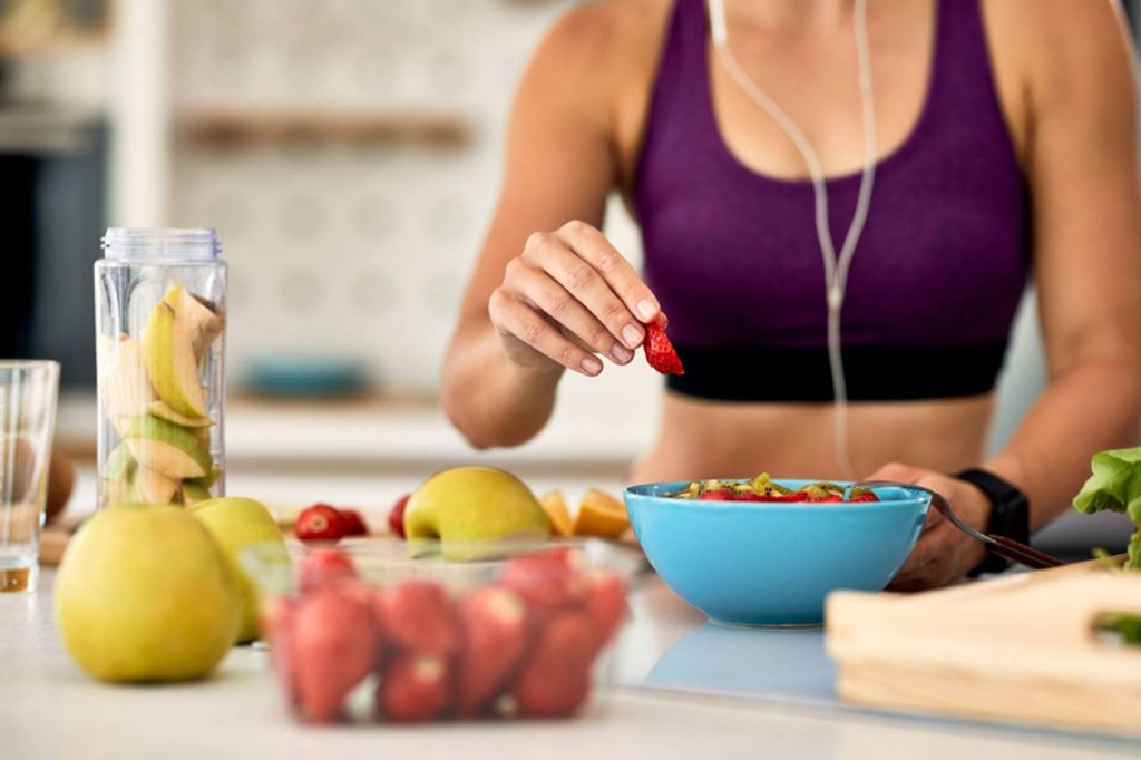 mulher montando salada de frutas