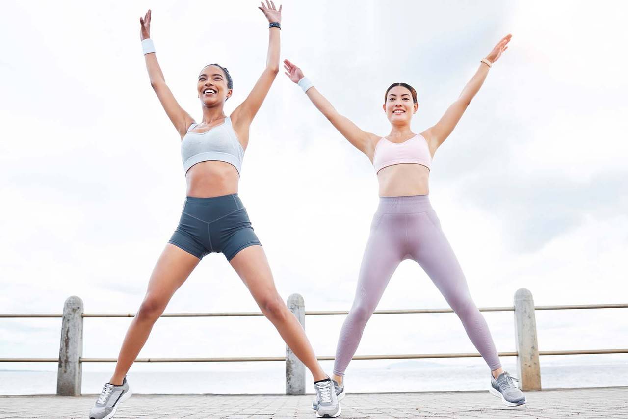 Imagem de uma dupla de modelos fazendo polichinelo ao ar livre de dia