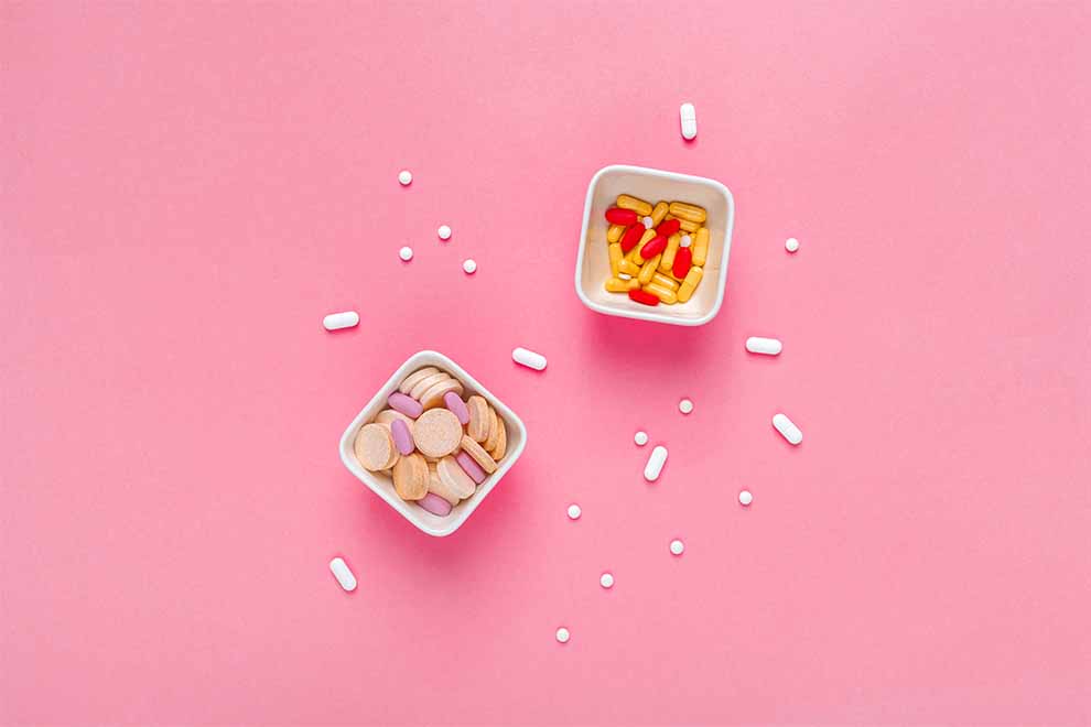 uso excessivo de medicamentos dois pequenos potes com muitos remédios em cima de uma mesa rosa