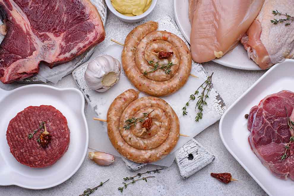 Variedade de carnes cruas em uma mesa de preparo culinário.