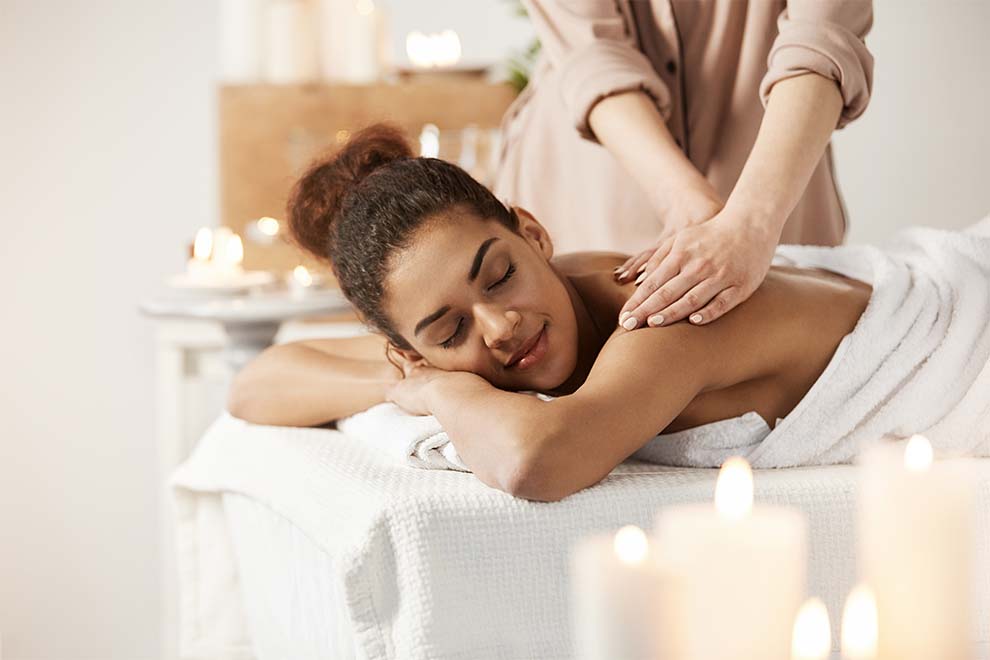 mulher recebendo massagem em um spa com velas aromaticas em volta