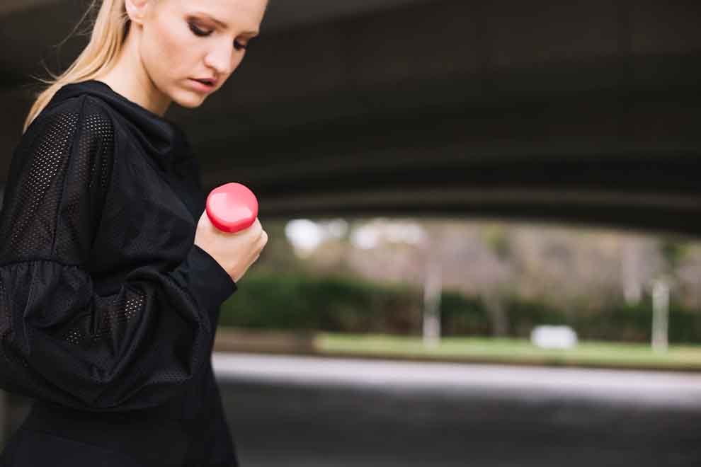 Mulher segurando um haltere rosa em treino