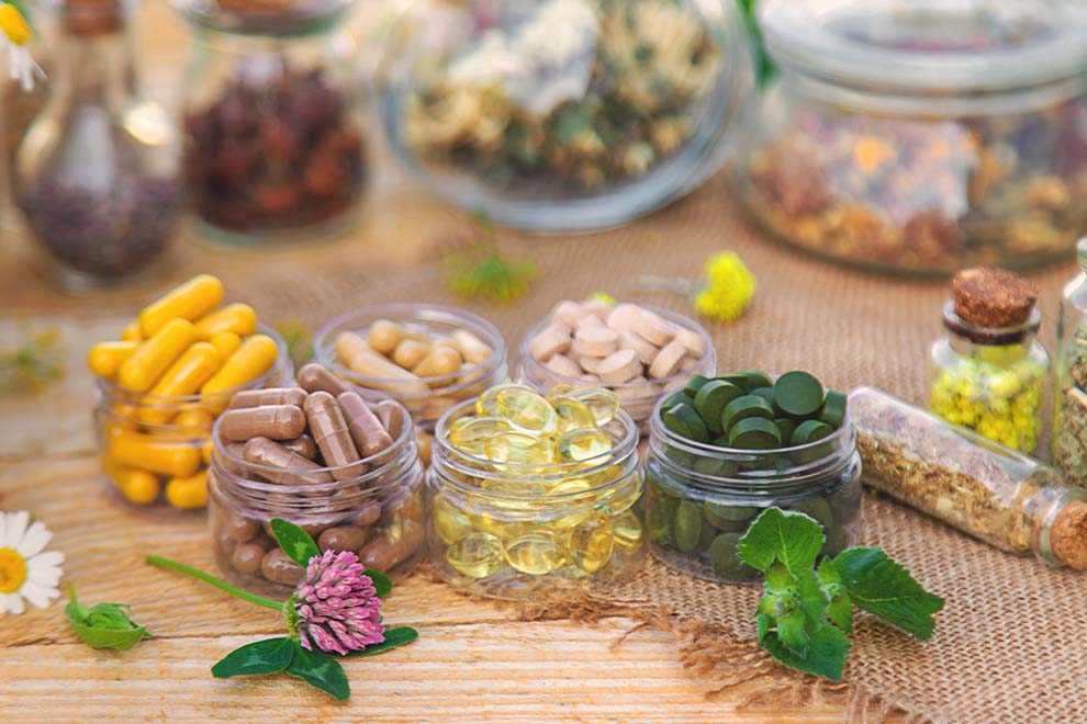 vários tipos de suplementos naturais dentro de um pequeno pote em acrilico em uma mesa de madeira natural