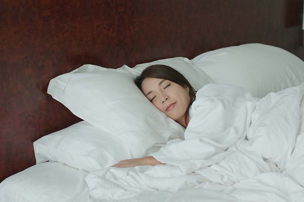 mulher tendo uma boa noite de sono em sua cama