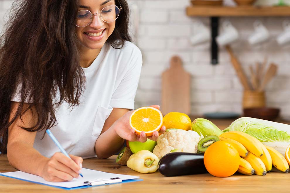Mulher escrevendo enquanto segura uma laranja