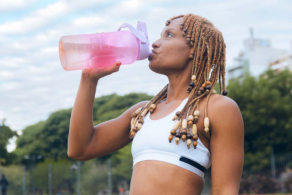 Mulher bebendo água de garrafa na prática esportiva