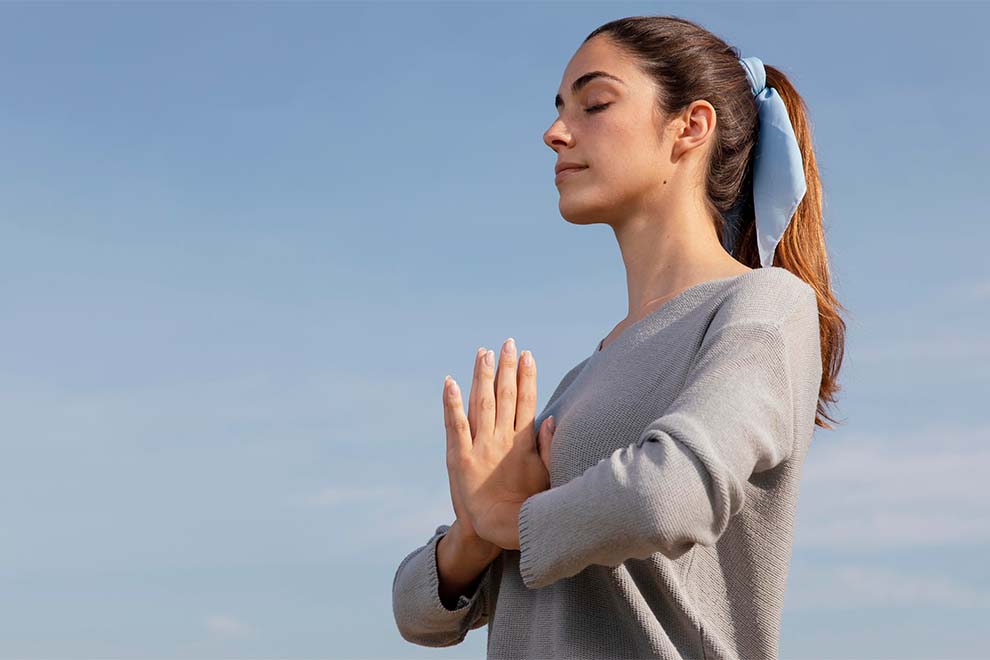 Mulher meditando ao ar livre com céu azul