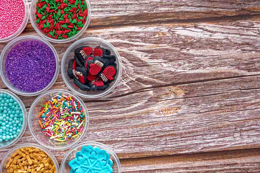 Confeitos coloridos em potes sobre mesa de madeira