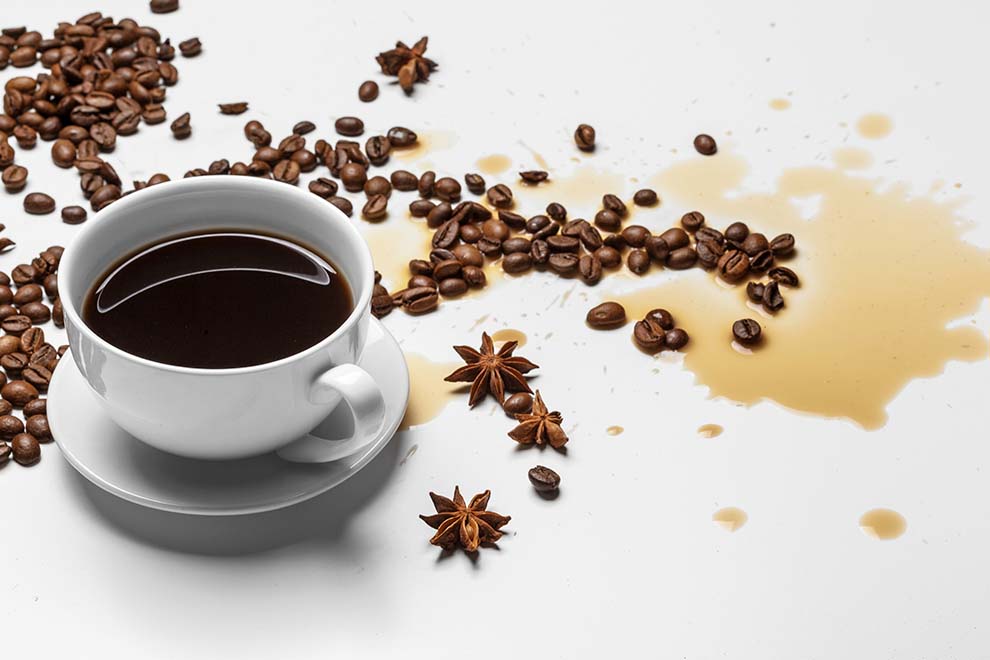 Café derramado com grãos e especiarias ao redor