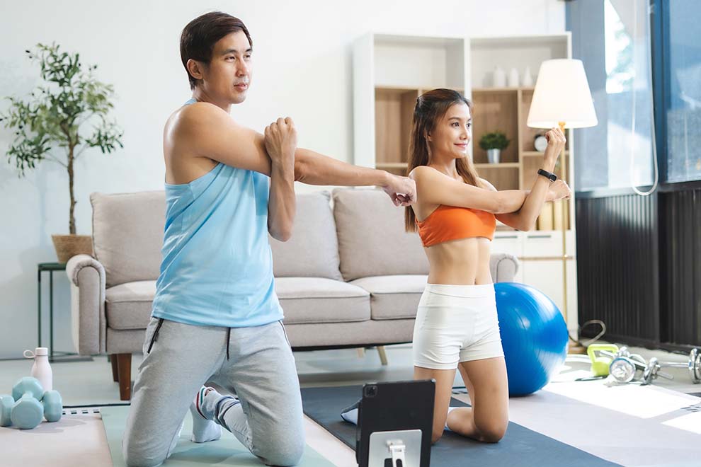 Casal fazendo alongamento em casa, fitness e bem-estar