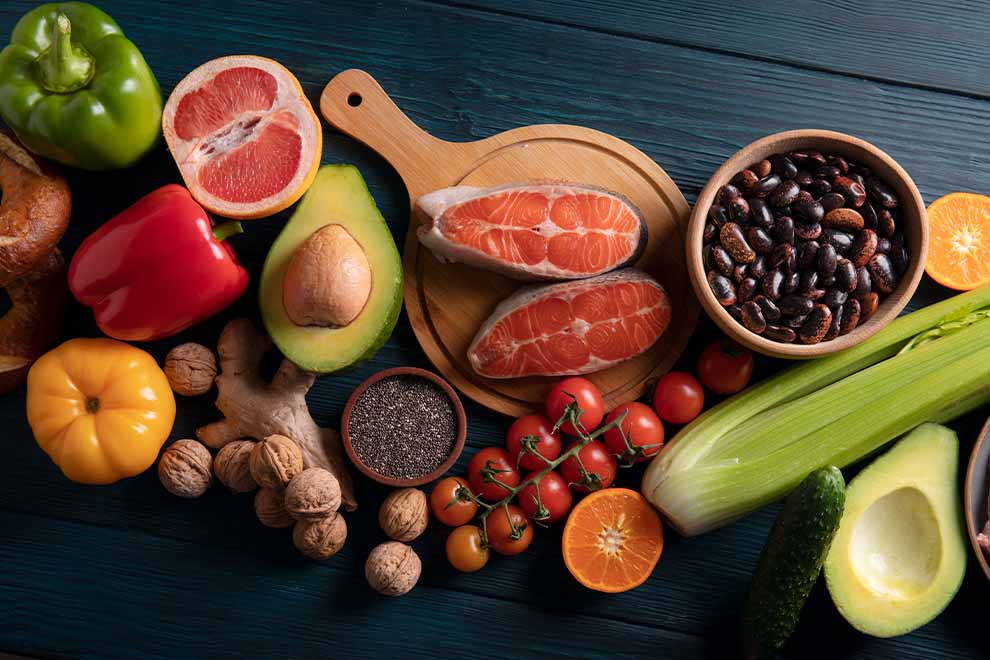 Frutas, legumes e peixes frescos em uma tábua de madeira.