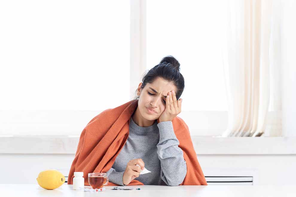 Mulher com dor de cabeça usando um lençol laranja.